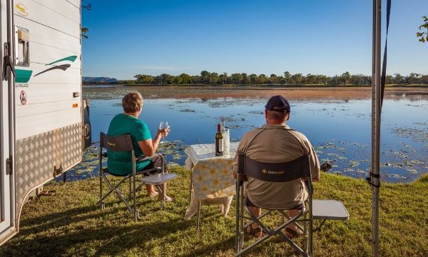 an elderly couple enjoying wine in front of a lake